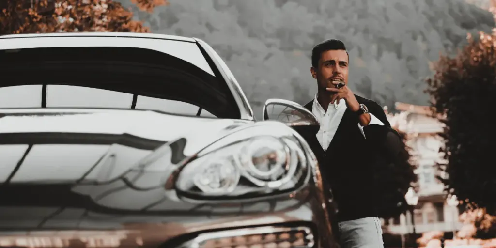 Homem rico, ao lado do seu porsche, representando Seguro Porsche 718 Boxster.