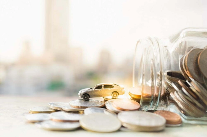 Miniatura de carro sobre moedas que estavam dentro de um pote. Explicando como economizar no seguro auto.