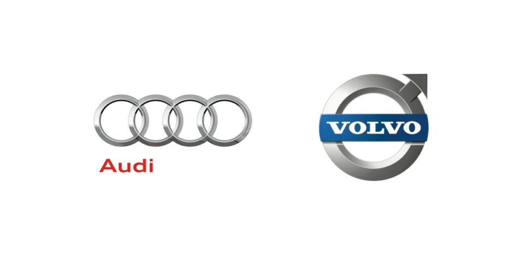 Logomarcas da Audi e da Volvo em paralelo. Respondendo: audi ou volvo qual oferece mais itens de seguranca no seguro.