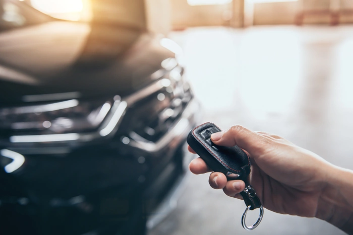 Proprietário aciona controle remoto de alarme do seu carro. Falando sobre os melhores seguros para carros.