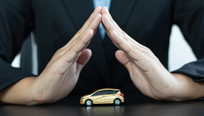 Um carro em miniatura com duas mãos o protegendo para representar a palavra-chave byd yuan pro seguro.