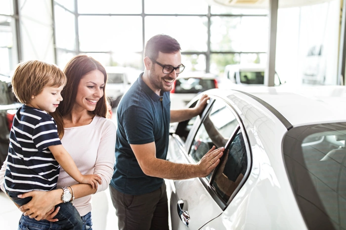 Família feliz observa carro novo que adquiriram por meio de consórcio. Explicando como fazer um consórcio de carros.