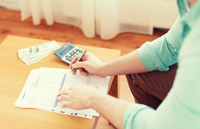 Mulher faz contas com calculadora. Falando sobre qual a diferença de consórcio para financiamento.