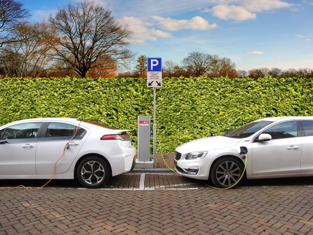 Dois carros híbridos carregando em ponto de energia. Falando sobre seguro para carro híbrido.