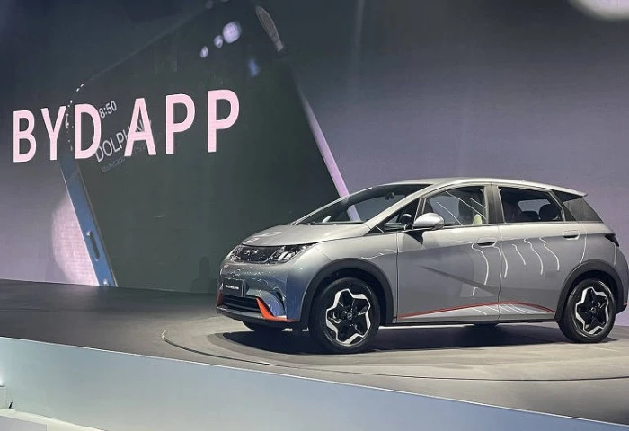 Veículo da BYD em área de exposição. Há a inscrição "BYD APP" na parede. Falando sobre o seguro de carro elétrico byd.