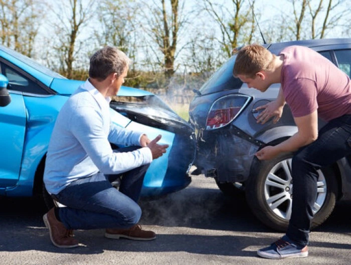 Dois homens discutem após colisão traseira entre seus veículos. Falando sobre os tipos de cobertura de seguro auto.